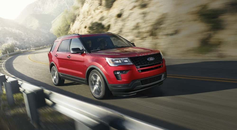 A used red 2019 Ford Explorer for sale is driving on a highway.