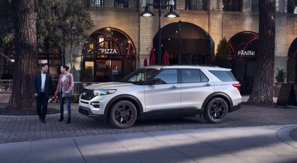 A white 2022 Ford Explorer parked near a pizza shop.