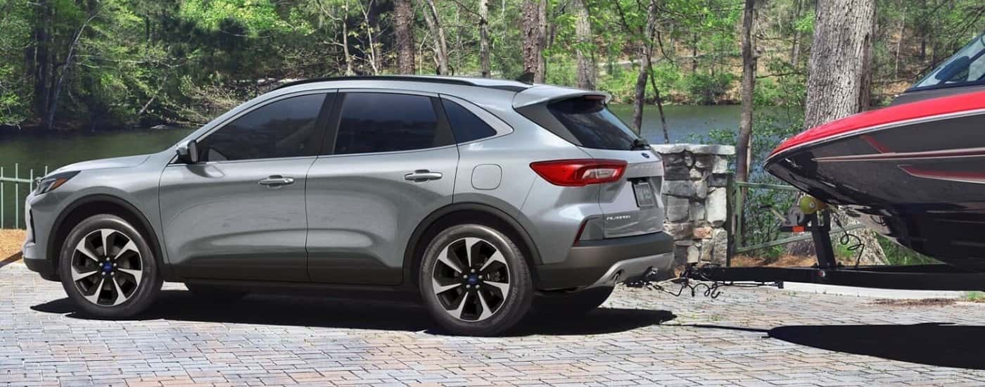Grey 2024 Ford Escape towing a boat near a lake