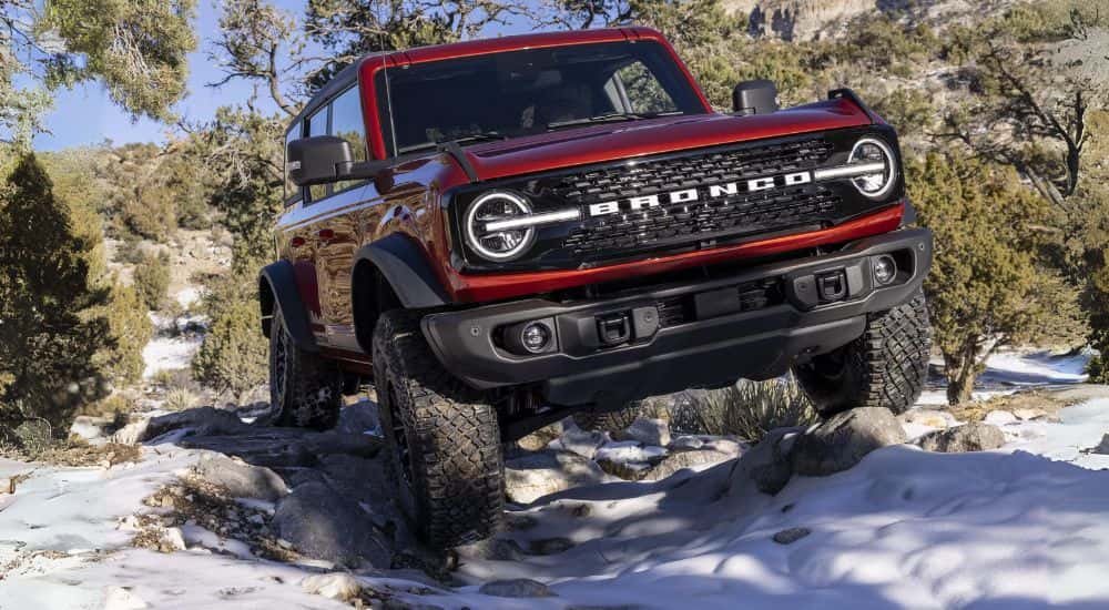 Red 2022 Ford Bronco driving through snow