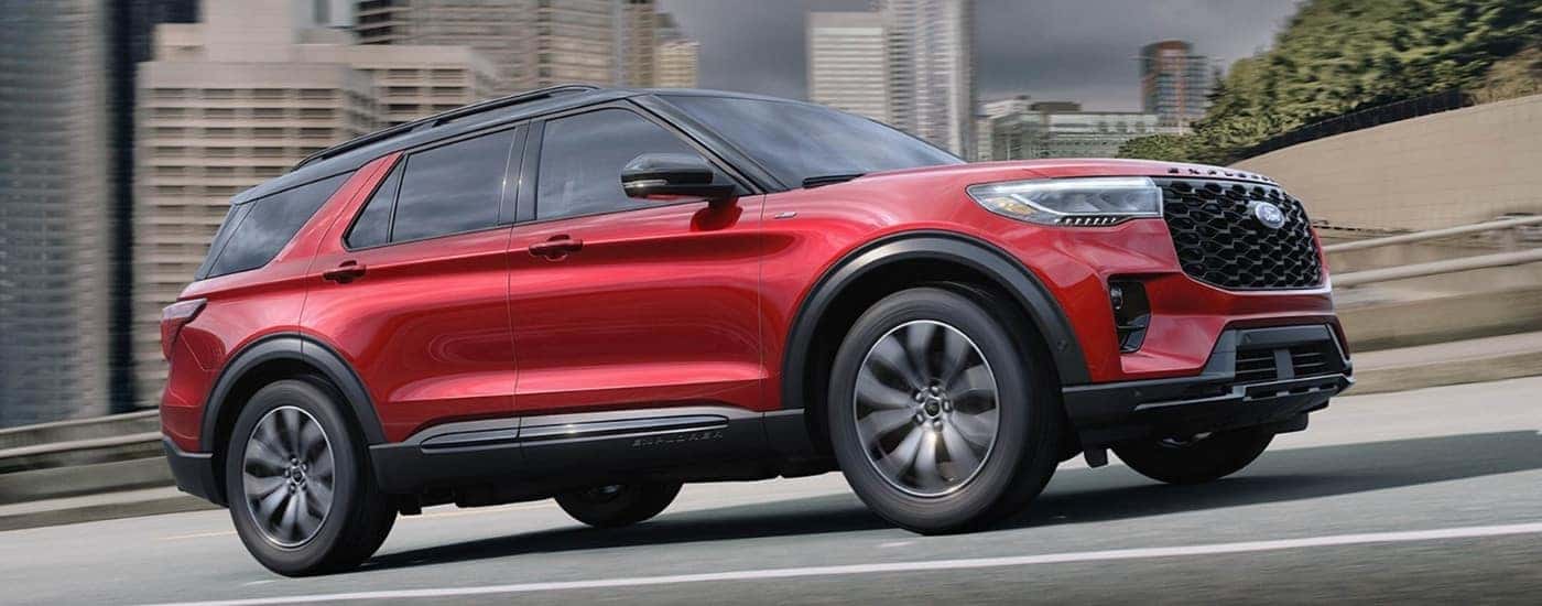 A red 2025 Ford Explorer ST-Line driving from a car dealership