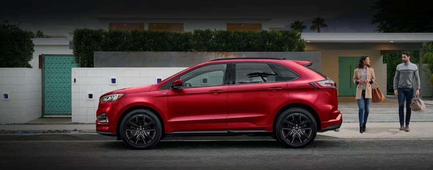 Two people walking near a red 2024 Ford Edge.