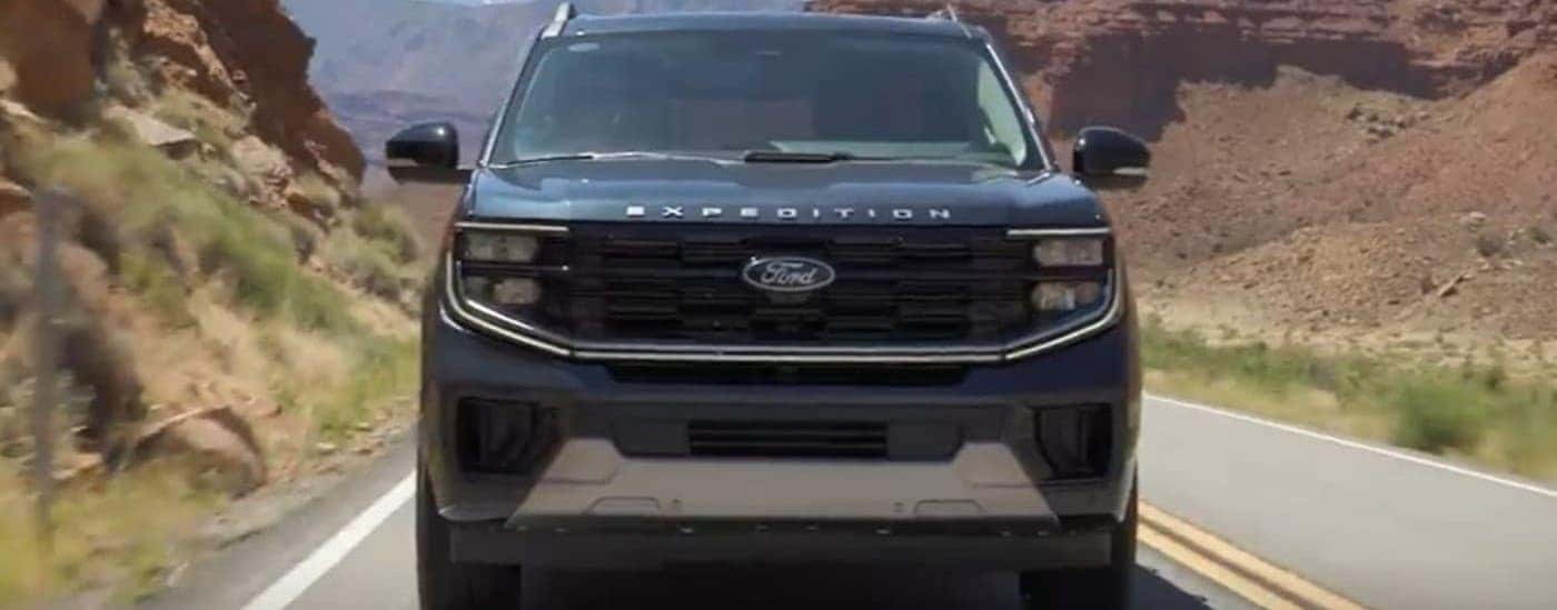 A black 2025 Ford Expedition driving on a highway.
