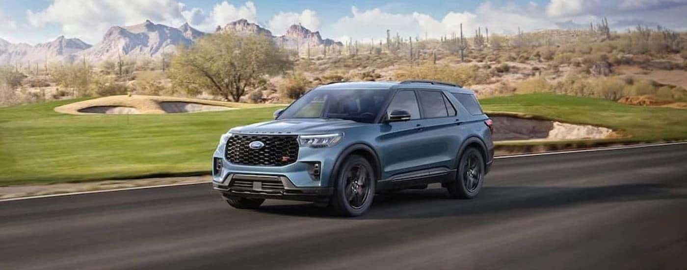 A blue 2025 Ford Explorer ST driving near a golf course.