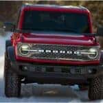 Red 2026 Ford Bronco driving through the snow