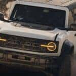 A white 2026 Ford Bronco is shown kicking up dust.