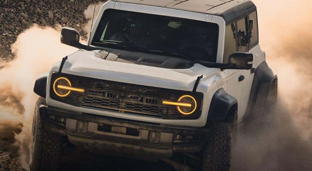 A white 2026 Ford Bronco is shown kicking up dust.