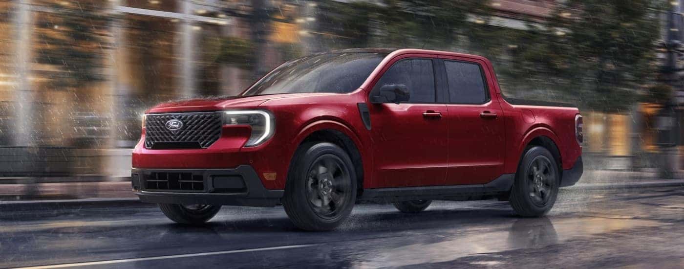 A red 2025 Ford Maverick driving on a rainy street.