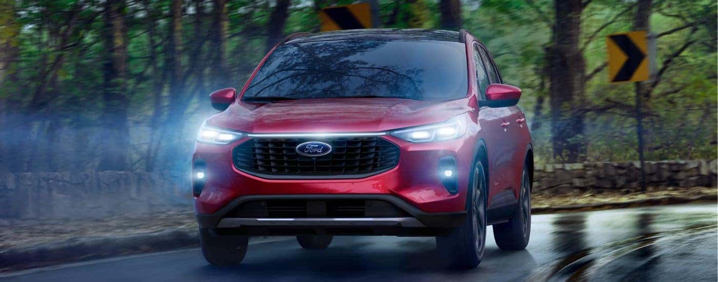 Red 2026 Ford Escape driving on a paved road.
