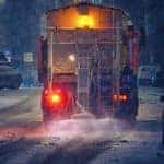 A salt truck is shown on a winter road.