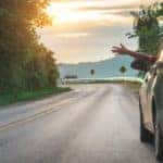 A hand is shown waving out of a car window.