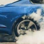 A close up shows a blue 2021 Ford Mustang doing a burnout.