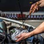 A mechanic is shown checking oil levels.