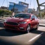 A red 2017 Ford Fusion is shown driving over a bridge.