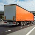 A tractor trailer is shown driving on a highway.