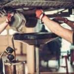 Two mechanics completing an oil change is shown.