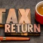A tax return reminder is shown beside a pen and a coffee cup.