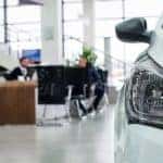 A cars headlight is shown in a dealerships showroom.