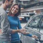 A couple is shown looking at cars at a dealership.