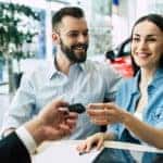 A couple is shown accepting car keys from a salesperson.