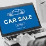 A person using their laptop to car shop online is shown.