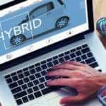 A man using a laptop to car shop online is shown.