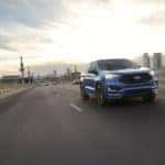 A blue 2021 Ford Edge is shown driving on a highway.