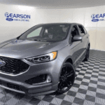 A silver 2021 Ford Edge is shown parked in a showroom.