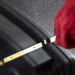 The oil level of a vehicle is being checked on a dipstick.