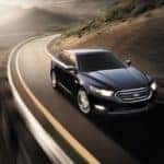 A black 2014 Ford Taurus Limited is shown rounding a corner.