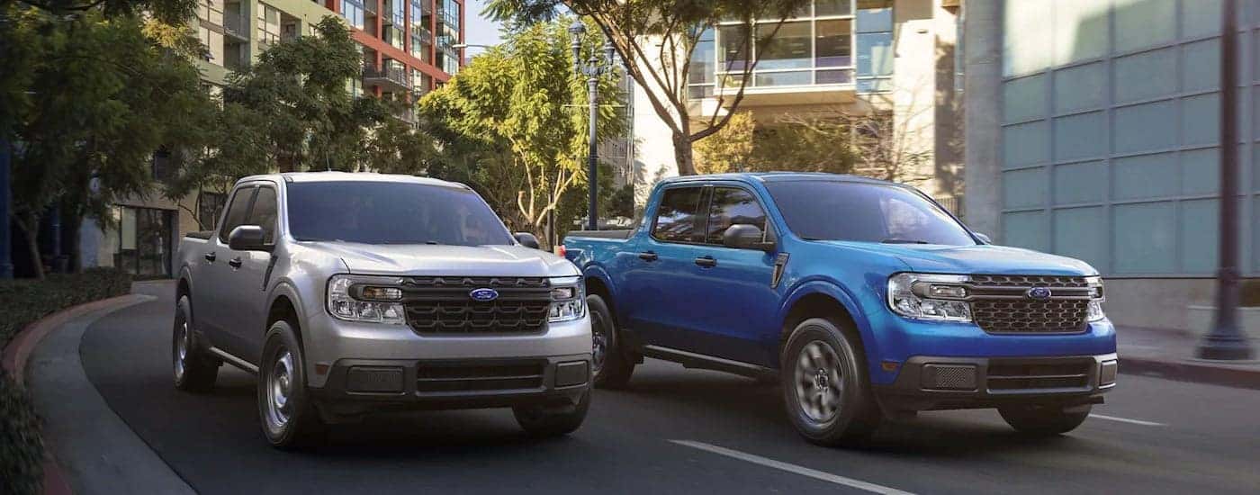 A blue and a silver 2022 Ford Maverick are shown driving on a city street.