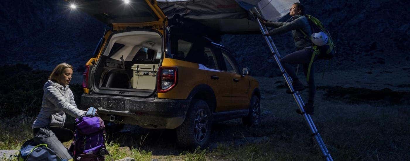 A yellow 2022 Ford Bronco Sport is shown at a campsite at night.