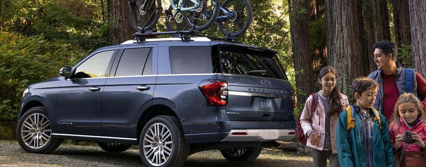 A blue 2022 Ford Expedition Outfitters Package is shown from a rear angle at a hiking trail.