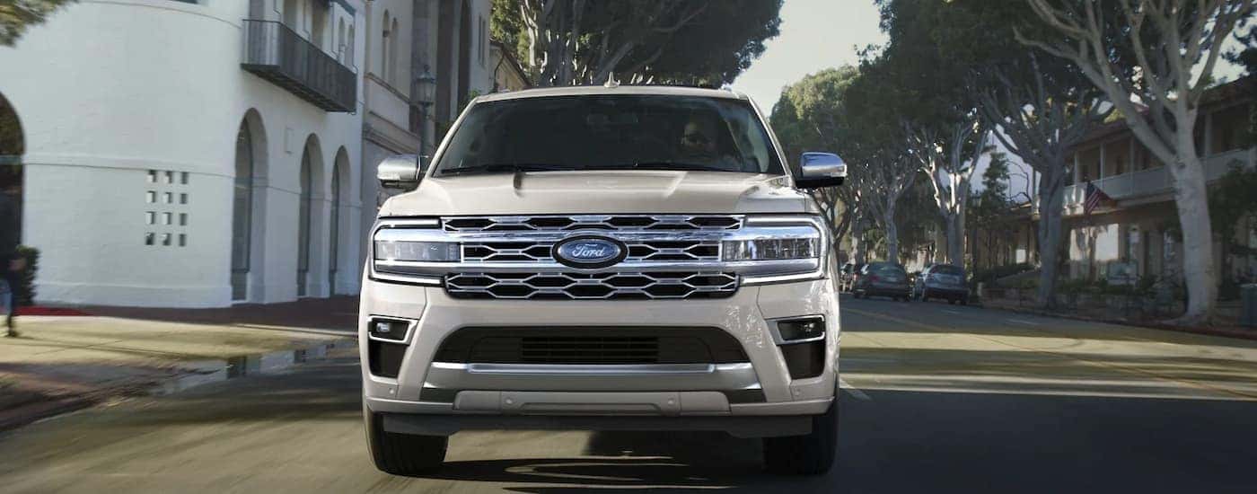 A white 2022 Ford Expedition Platinum is shown from the front driving on a city street.