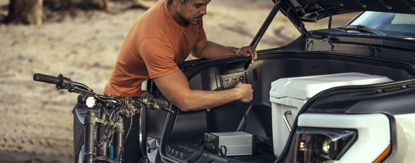 A person is shown charging supplies in the frunk in a 2022 Ford F-150 Lightning.