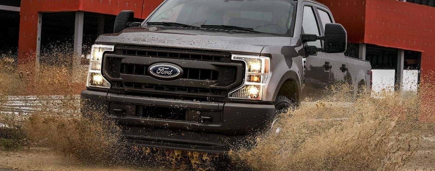 A brown 2022 Ford F-350 XL is shown driving through a muddy puddle.