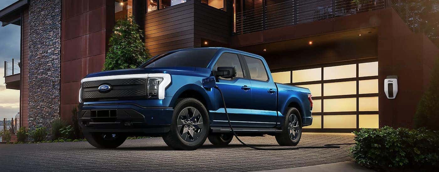 A blue 2023 Ford F-150 Lightning is shown charging during a 2023 Ford F-150 vs 2023 Chevy Silverado 1500 comparison.