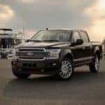 A black 2019 Ford F-150 Limited is shown parked at a marina.