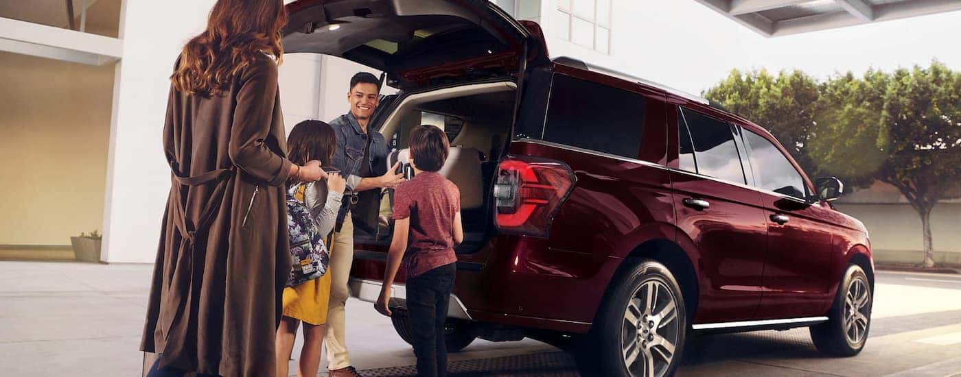 A family is shown putting luggage in the cargo area of a red 2023 Ford Expedition.