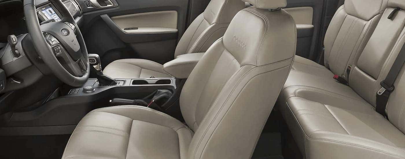 The tan interior of a 2023 Ford Ranger Supercrew shows two rows of seating and the center console from the side.