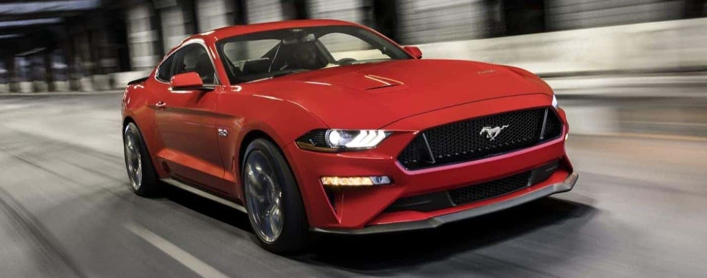 A red 2022 Ford Mustang is shown from the front driving on an open road.