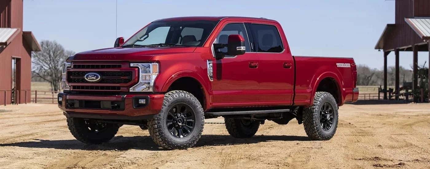A red 2022 Ford F-250 Lariat is shown parked in an open dirt area.