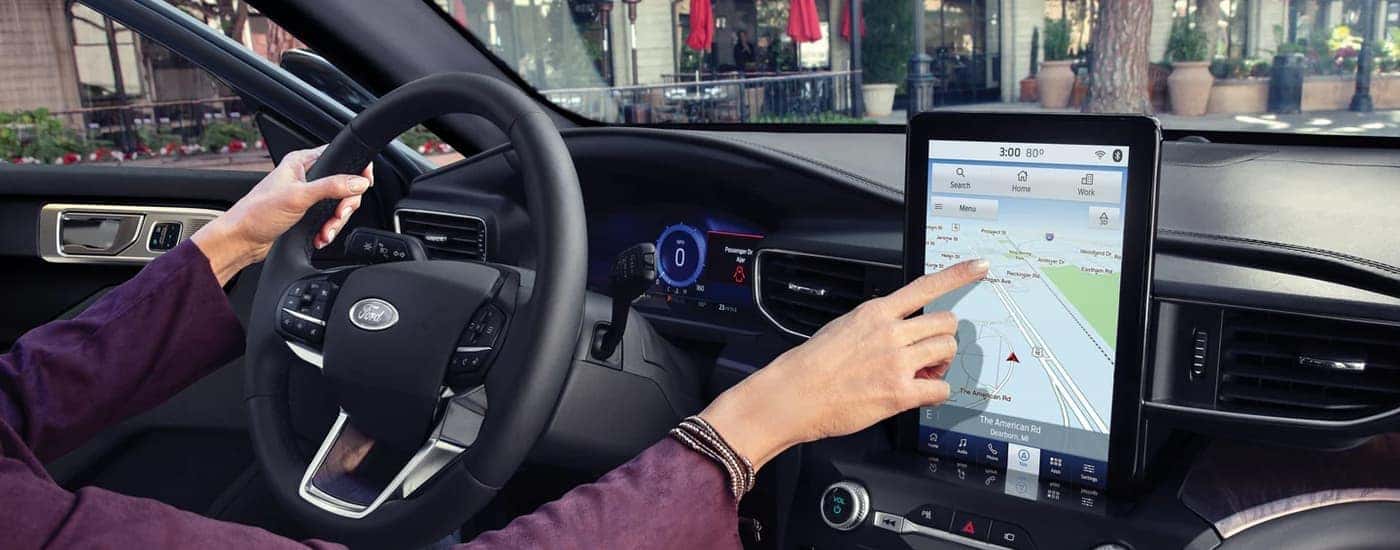 A person is shown using the map on the infotainment screen in a 2023 Ford Explorer.