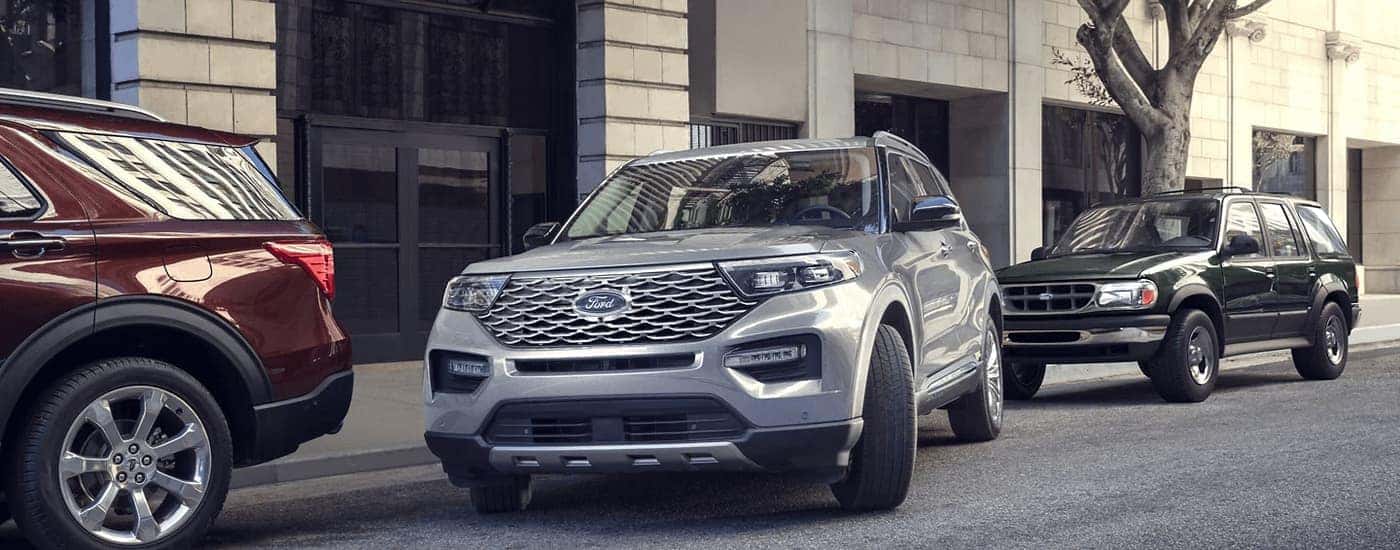 A silver 2023 Ford Explorer is shown pulling out of a parking spot on the side of a city street.