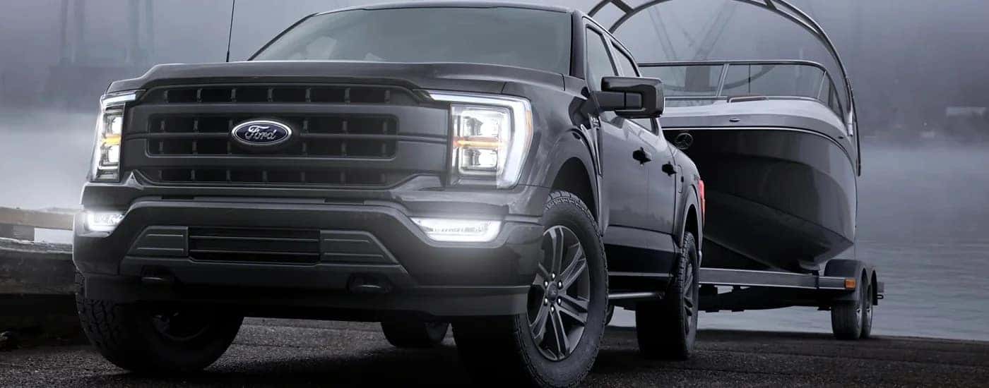 A black 2023 Ford F-150 towing a boat through fog.