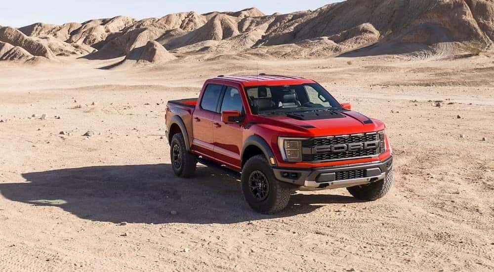 A red Ford F-150 Raptor is shown parked on the sand after off-roading.
