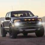 One of the most popular Ford F-150 for sale, a silver 2023 Ford F-150 Raptor, is shown parked on the sand.