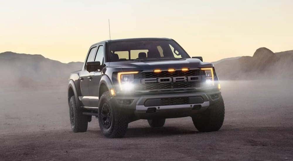 One of the most popular Ford F-150 for sale, a silver 2023 Ford F-150 Raptor, is shown parked on the sand.