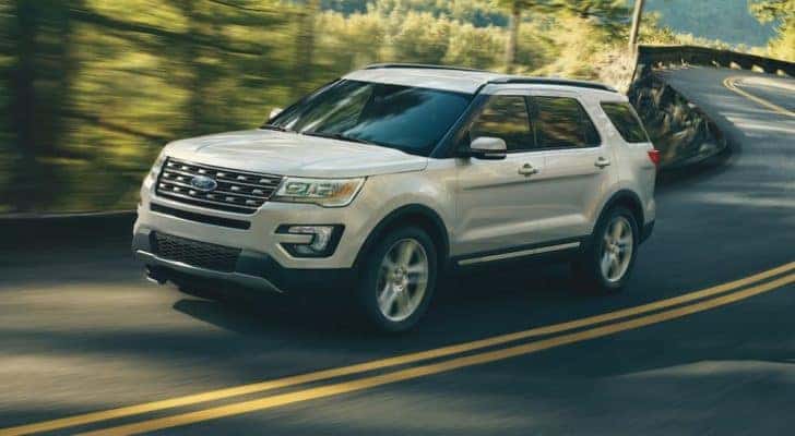 A white 2018 Ford Explorer is shown driving on a wooded road.