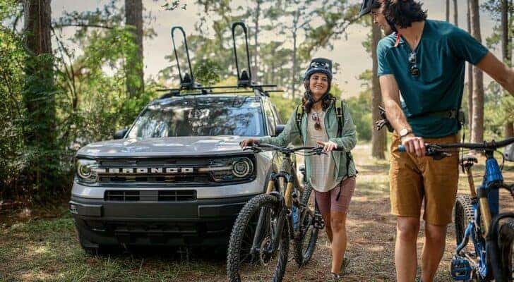 A white 2023 Ford Bronco Sport is shown from the front after two people unloaded bikes from it.